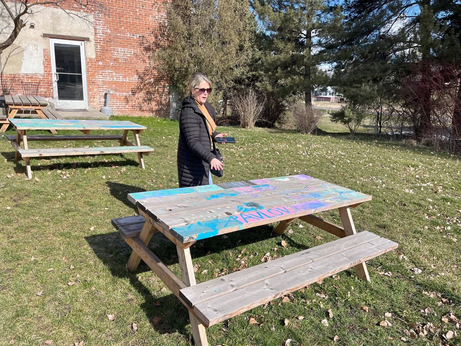 Plain wooden picnic tables have been painted in child-like pastel designs