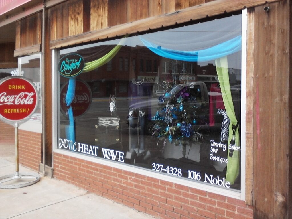 A downtown building window has a a display of goods for business located far from downtown.