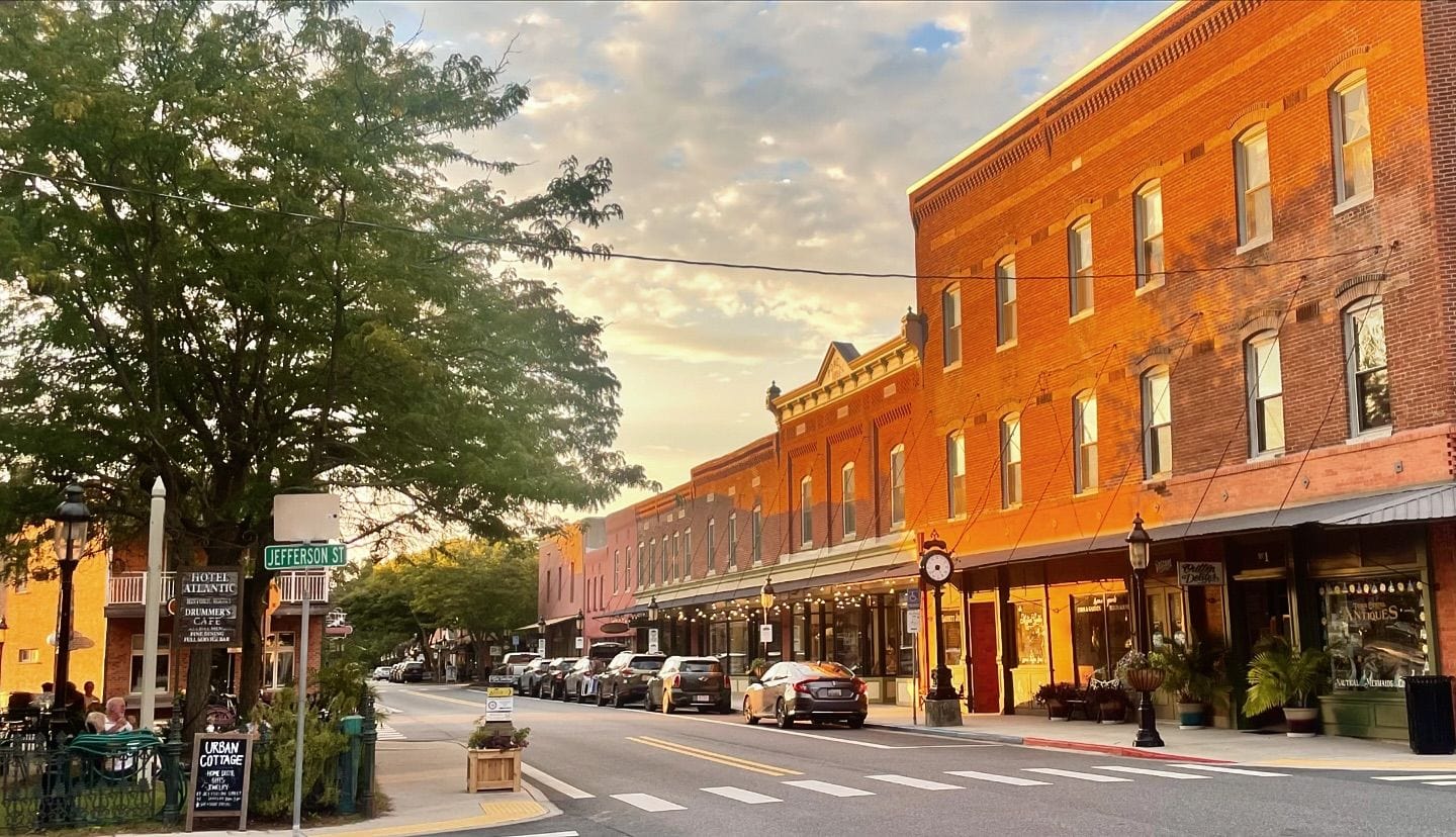 A small town downtown area, with golden sunlight streaming in and people enjoying a sidewalk eating area.