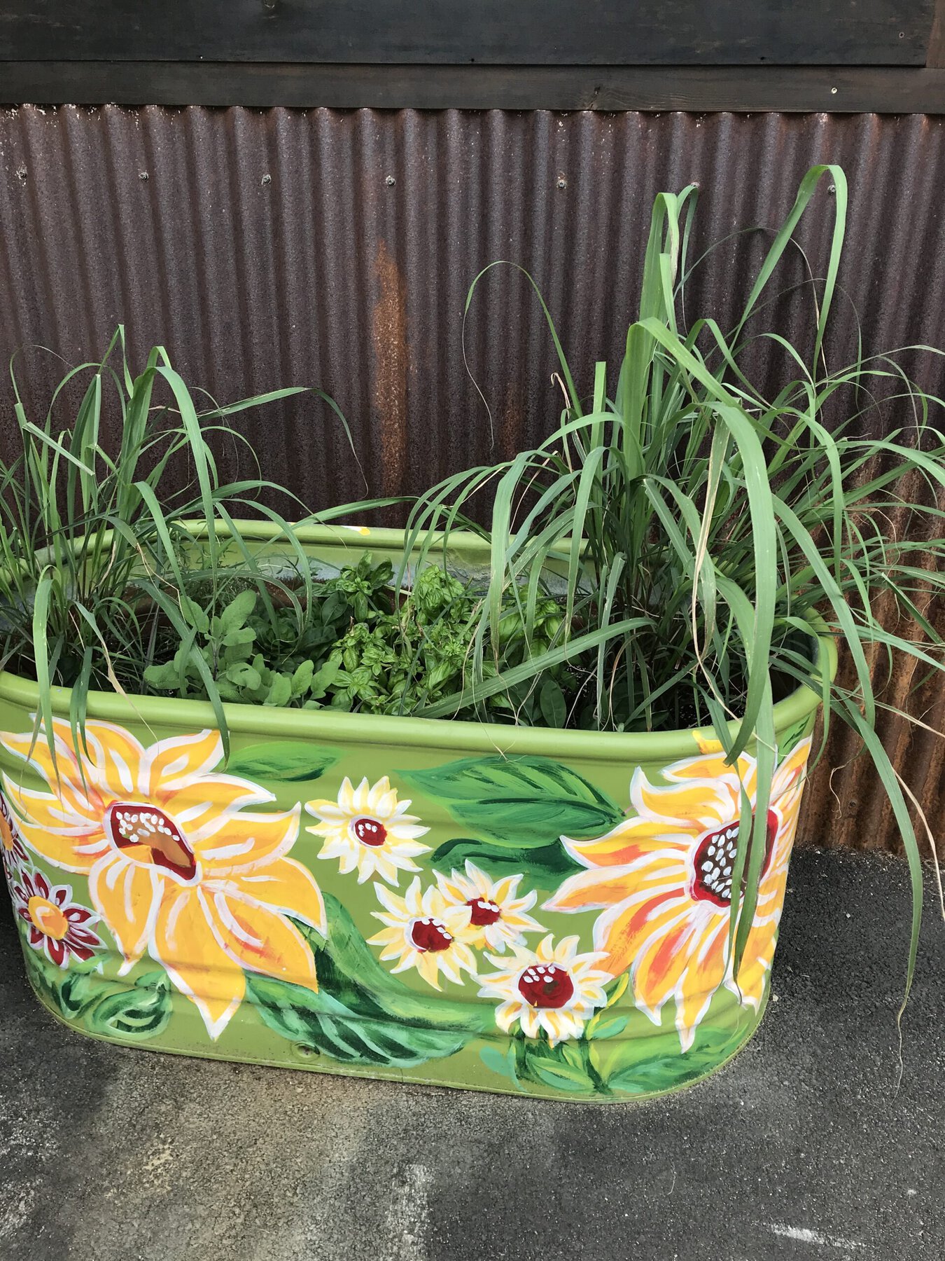 A small metal water tank has been converted to an herb garden planter and painted with bright flowers