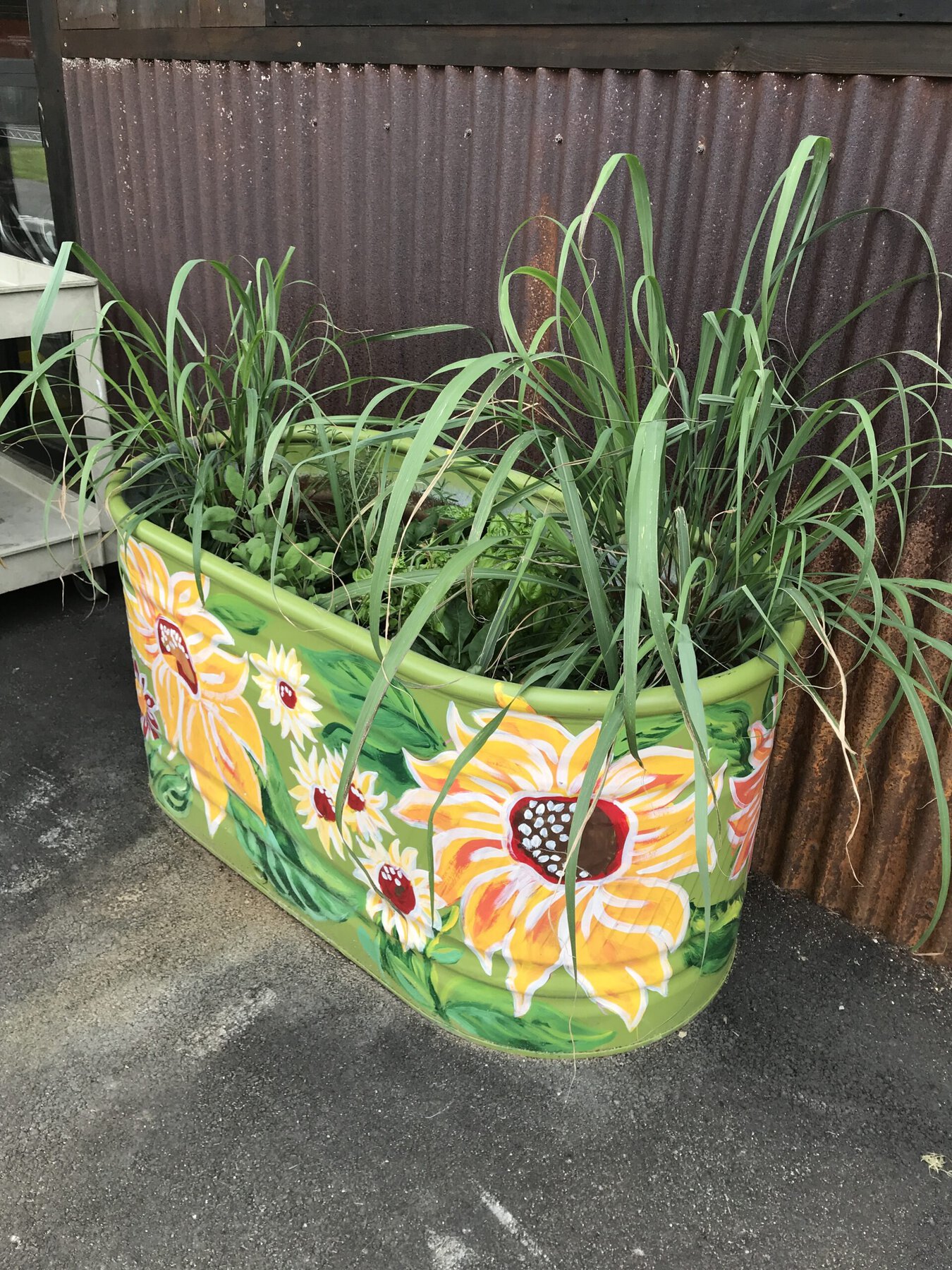 A small metal water tank has been converted to a planter and painted with bright flowers